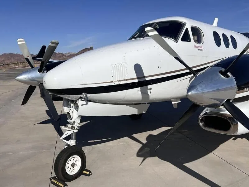 A detailed front-right view of the nose and propeller of a white and black turboprop aircraft.