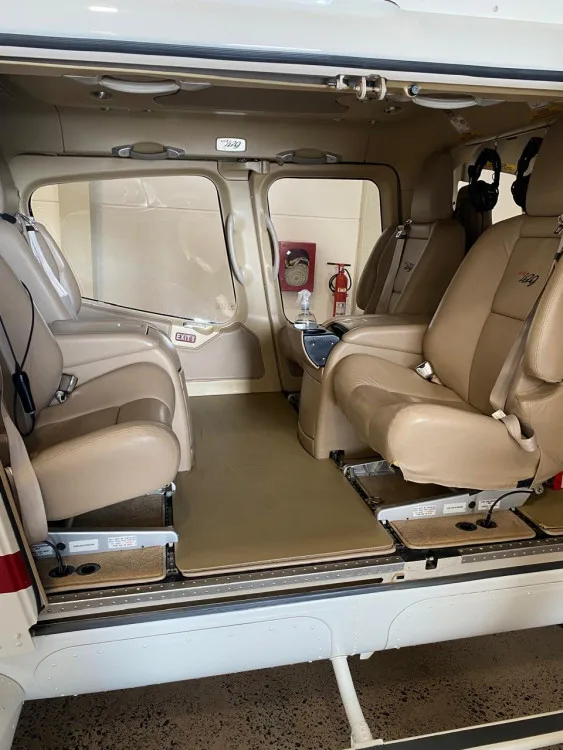 The tan leather interior cabin of a Bell 429 helicopter with two rows of seats visible through an open door.