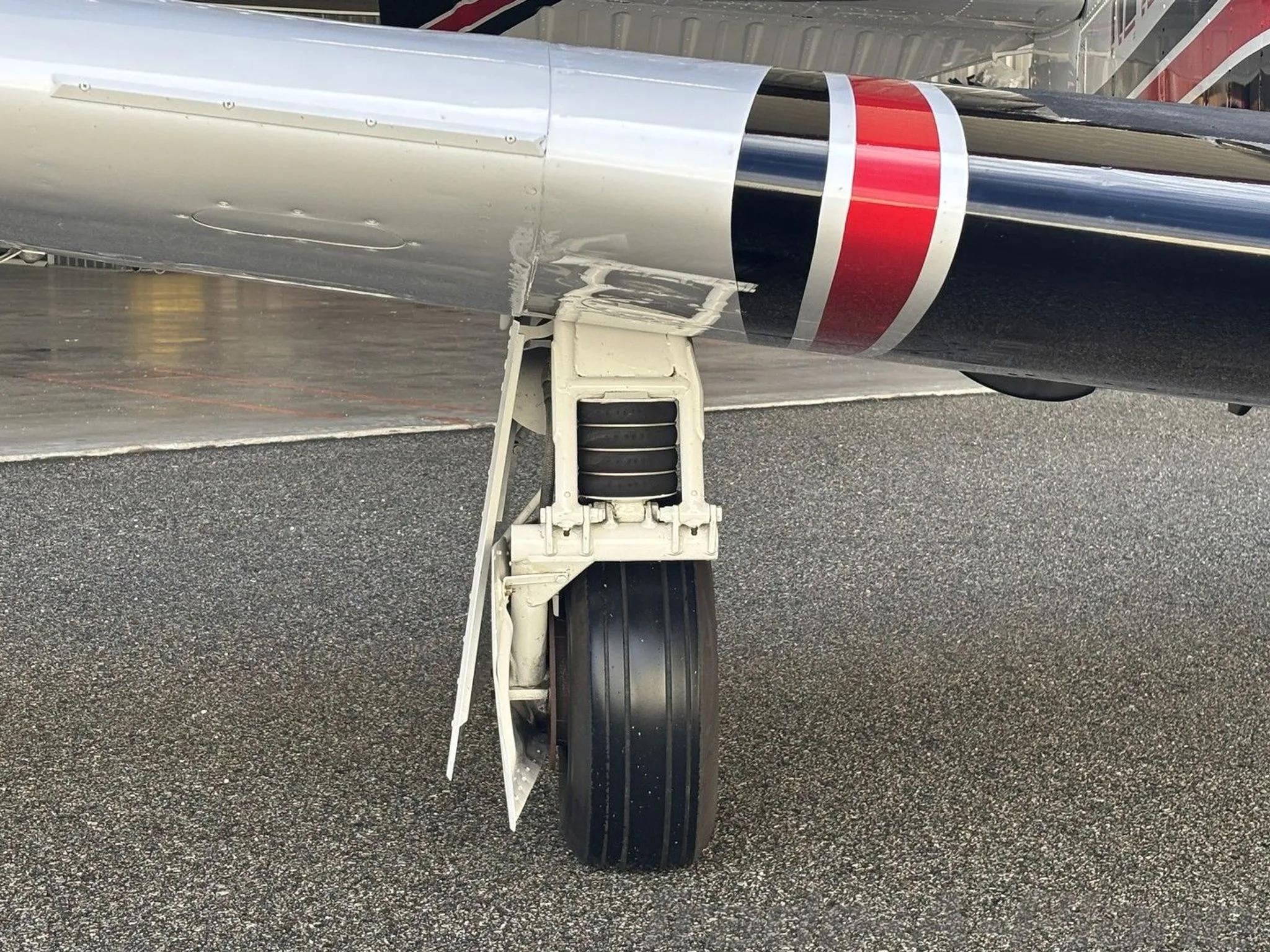 A close-up view of the main landing gear of a Mooney M20K aircraft, showing the tire and strut.