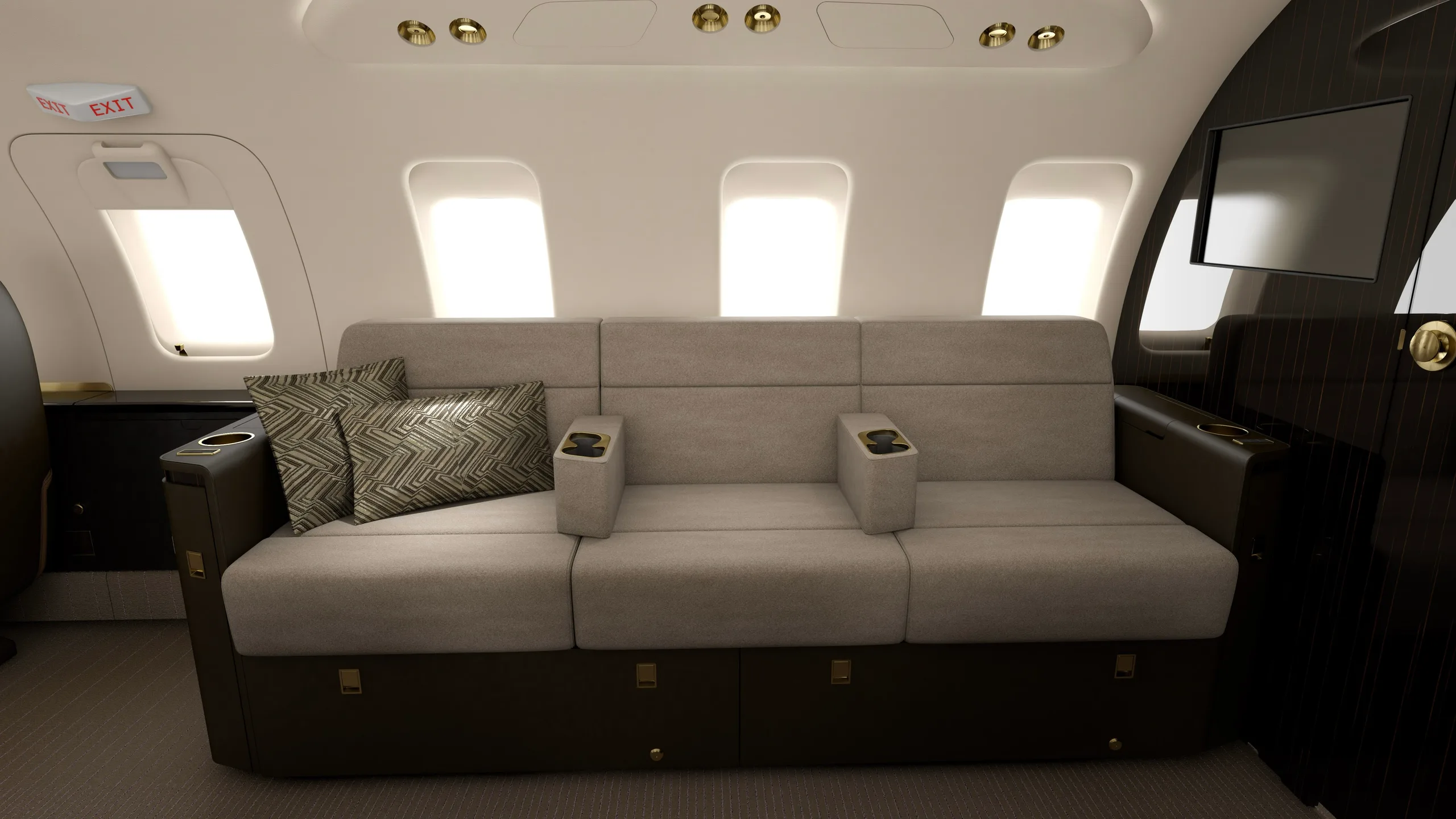 A grey three-seat sofa with patterned pillows inside a luxurious aircraft cabin.