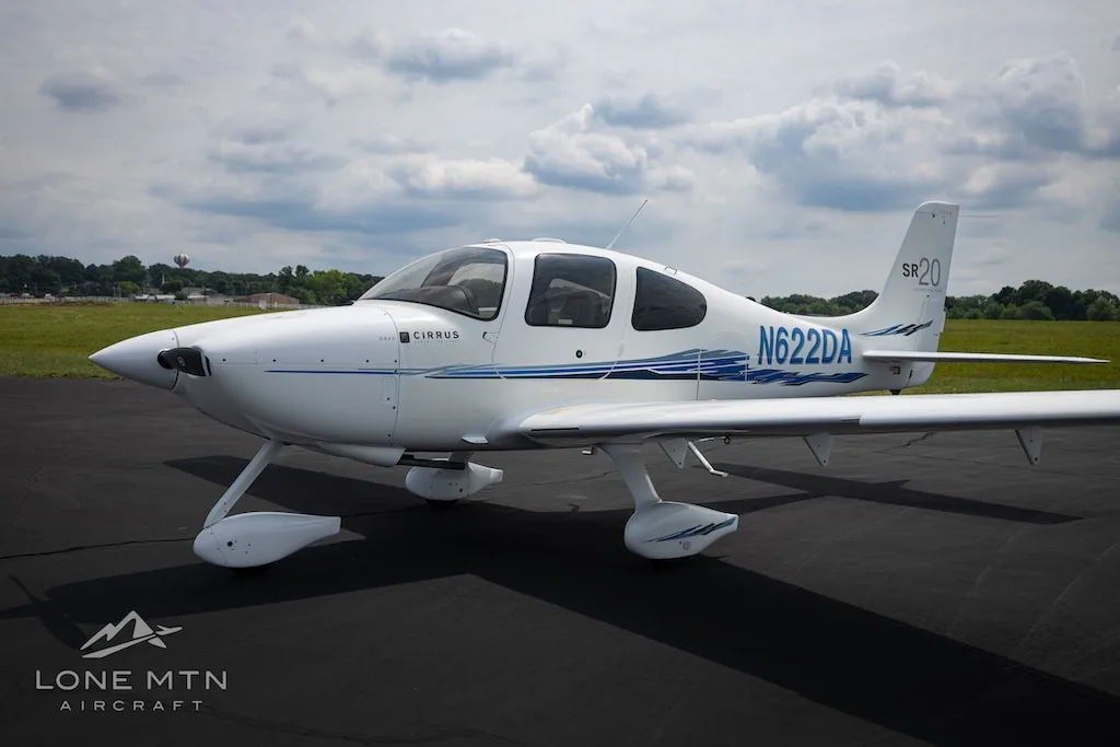 A white Cirrus SR20 aircraft with blue accents and tail number N622DA parked on an asphalt runway under a cloudy sky.