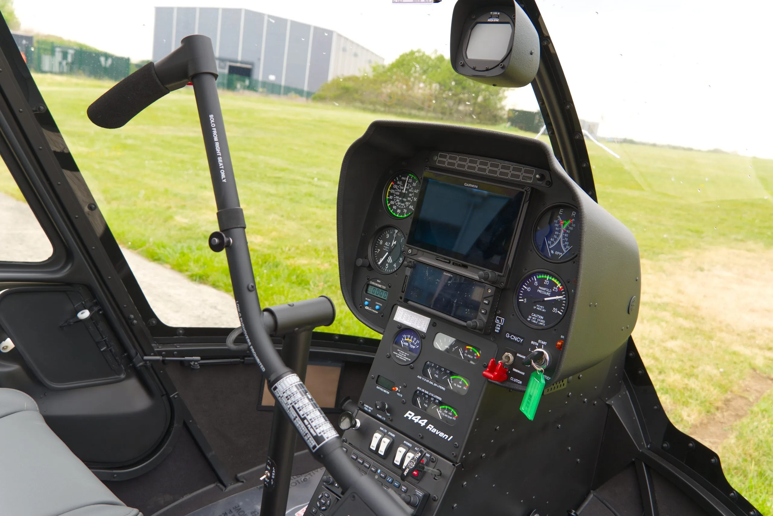 The instrument panel and controls of a Robinson R44 Raven I helicopter are shown from the pilot's perspective.