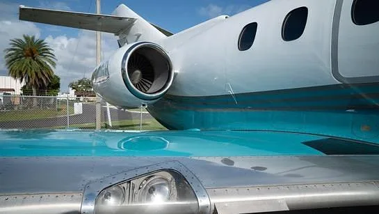 A close-up view of the engine and wing of a white and teal Hawker 800XP business jet.