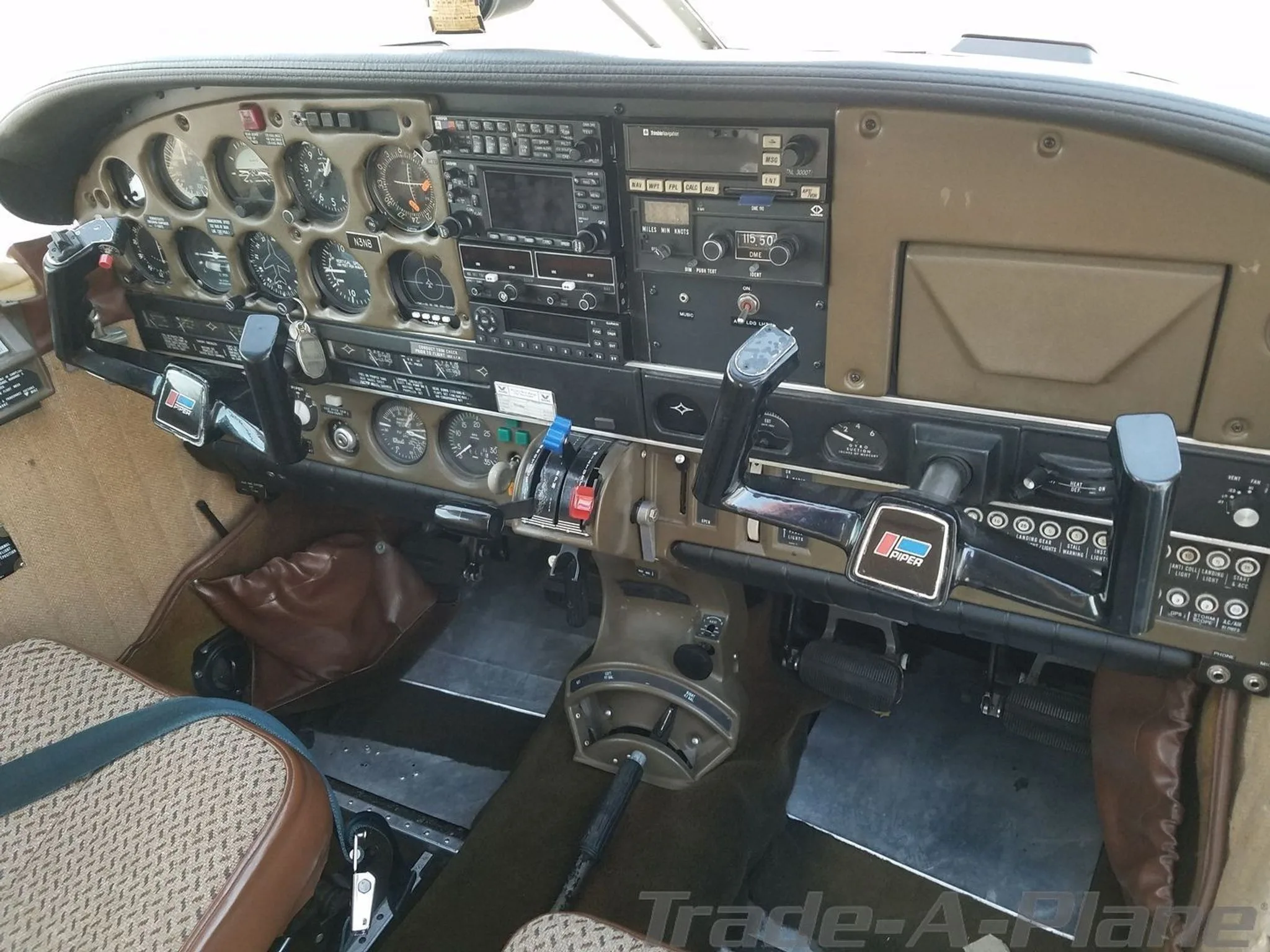 The cockpit of a Piper aircraft, showing the instrument panel with various gauges, radios, and control yokes.
