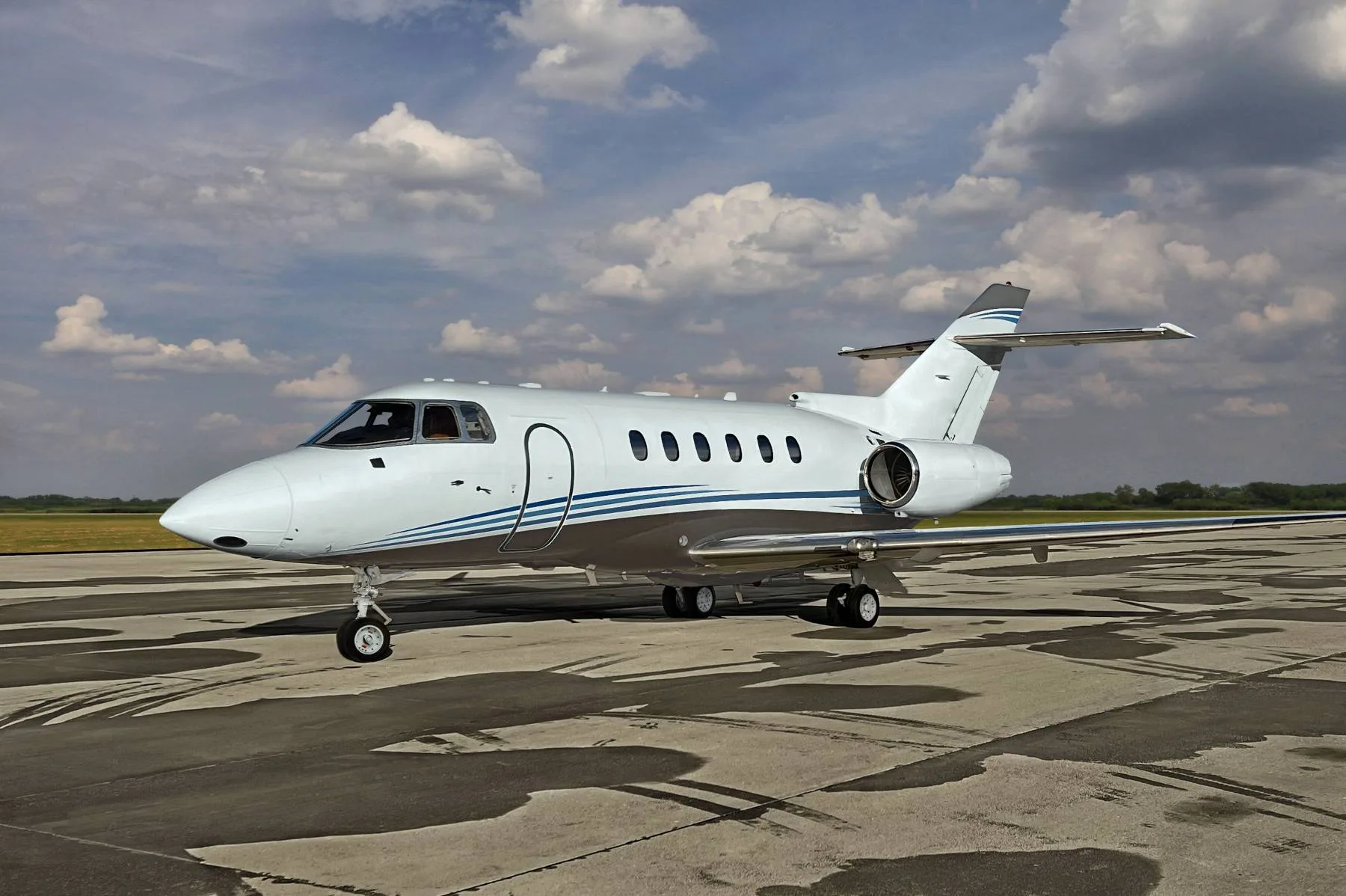 A white and blue Hawker 850XP sits on the tarmac under a cloudy sky.