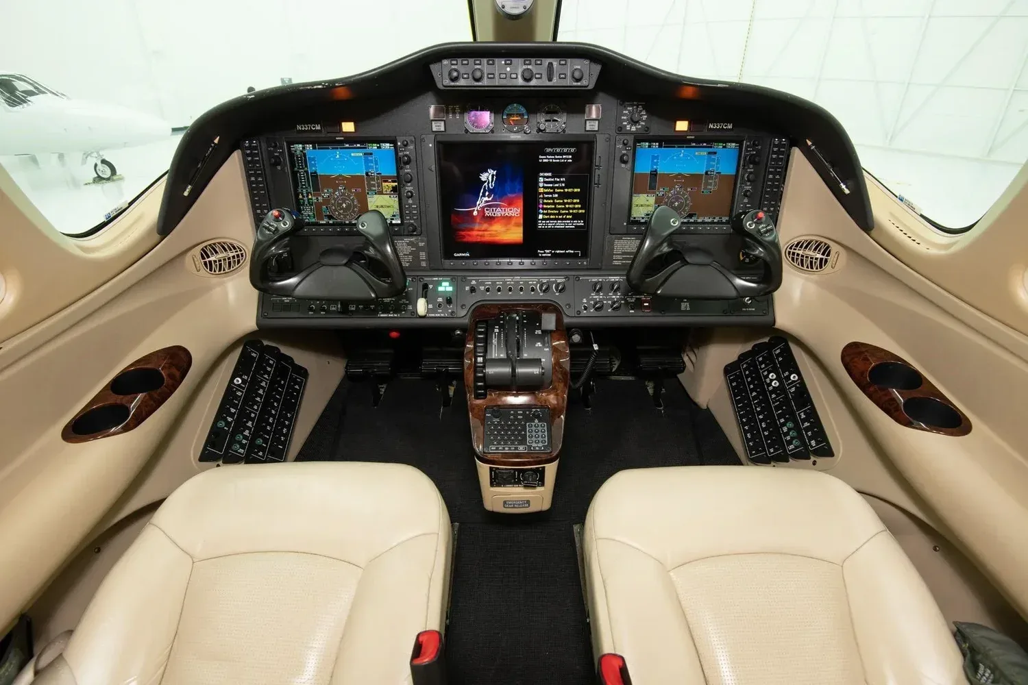 The cockpit of a Cessna Citation M2 with two beige pilot seats and a modern glass panel display.