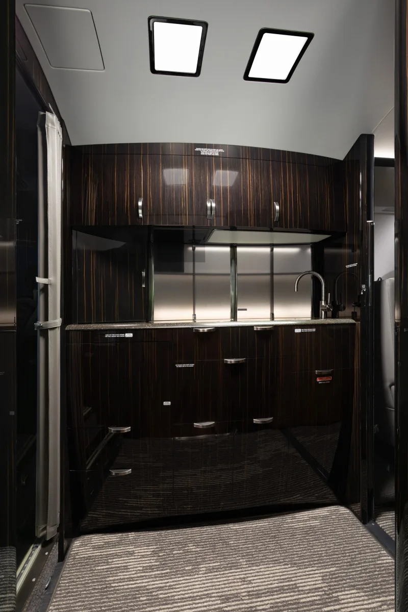 Galley area with dark wood cabinets and stainless steel backsplash.