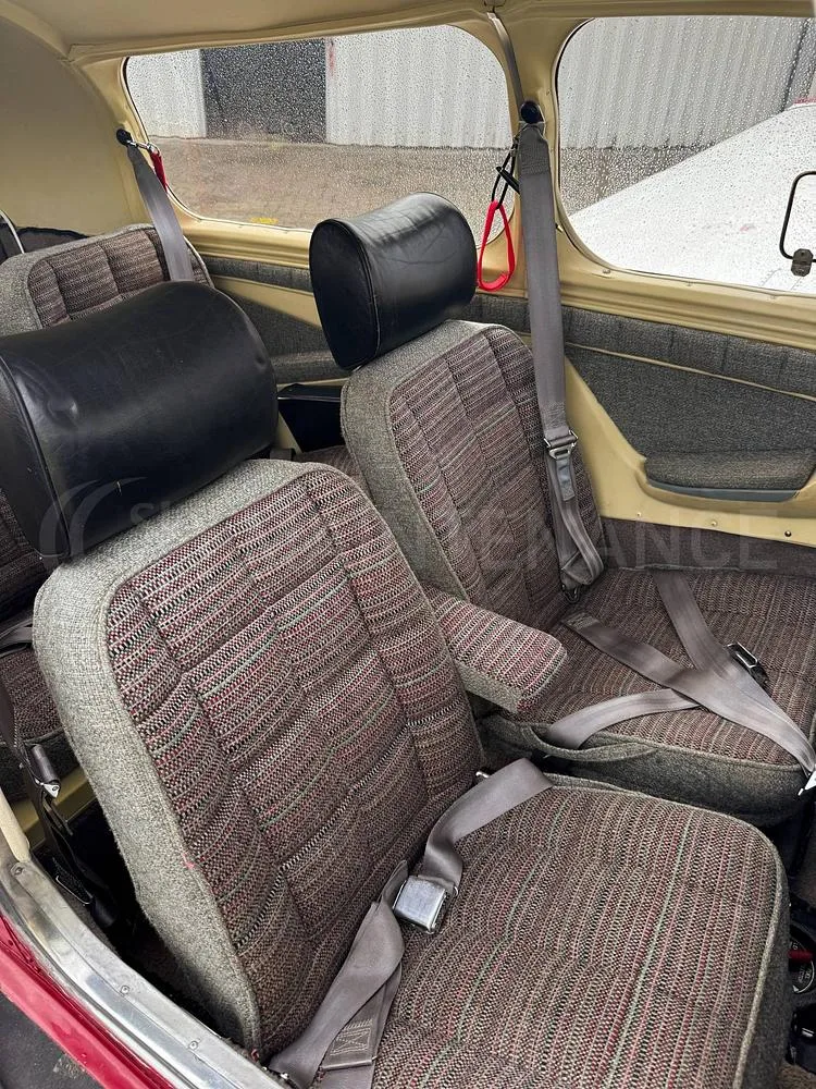 The front and middle row of seats in the aircraft's cabin, upholstered in a grey and red patterned fabric.
