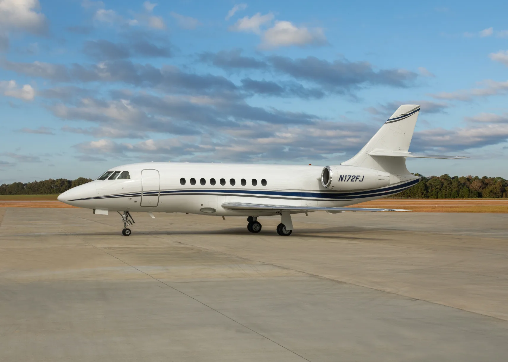 Dassault Falcon 900 on the tarmac with a white and blue paint scheme.
