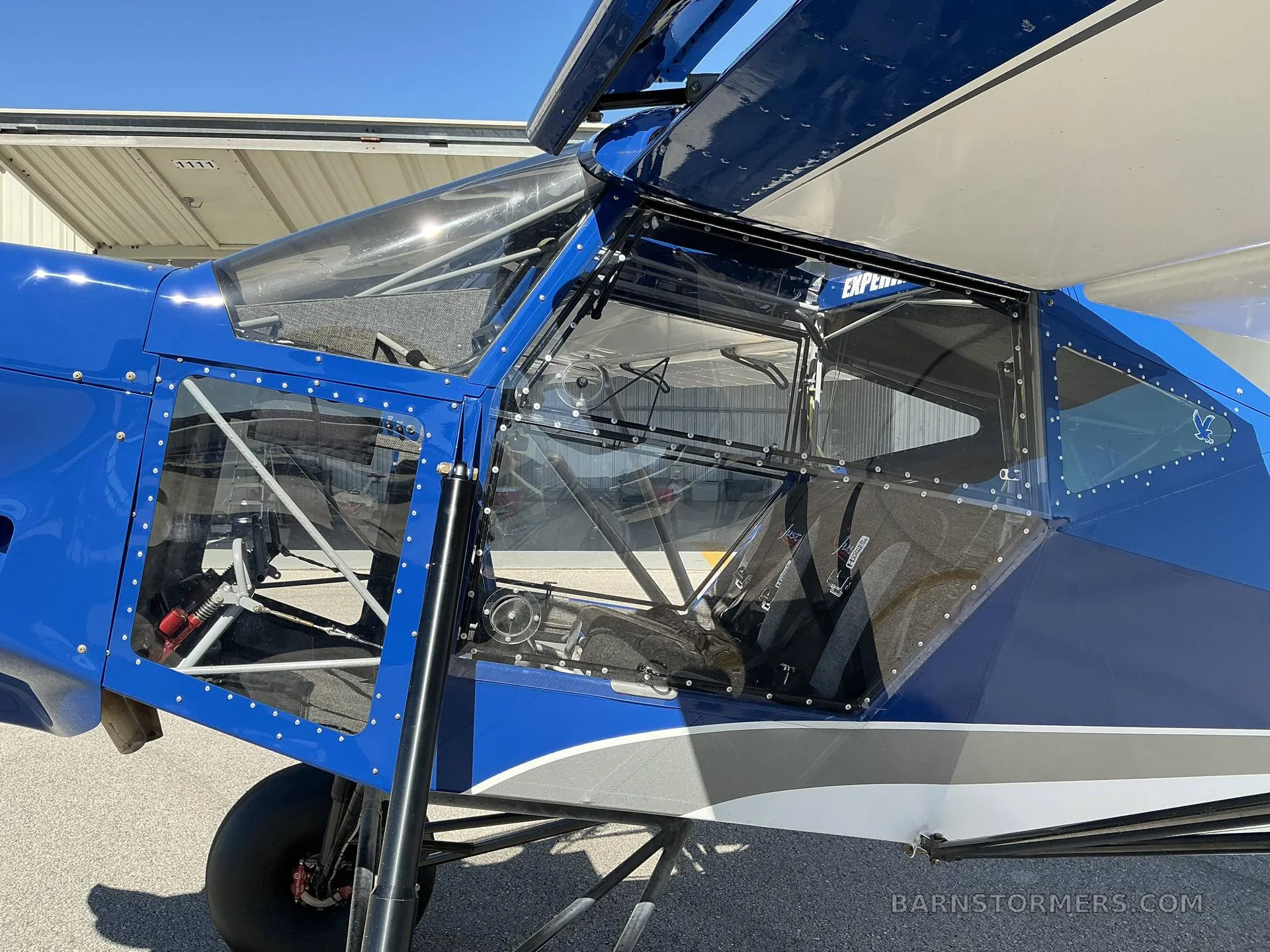 A close-up side view of the transparent cabin and cockpit area of the blue and white SuperSTOL aircraft.