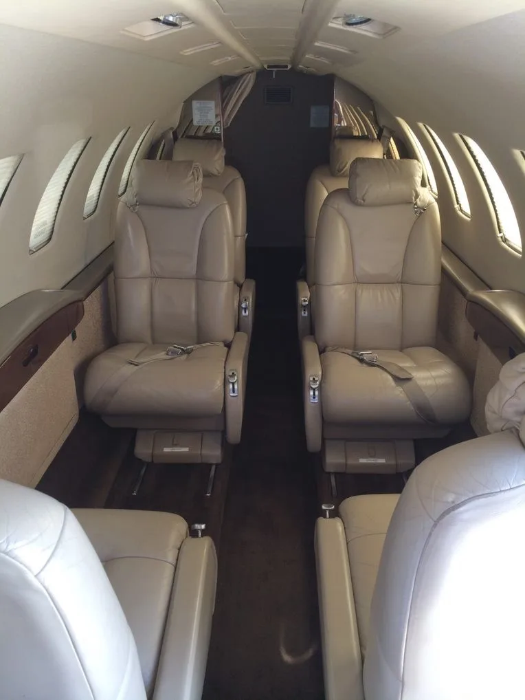 Aircraft cabin with tan leather seats and brown carpet.