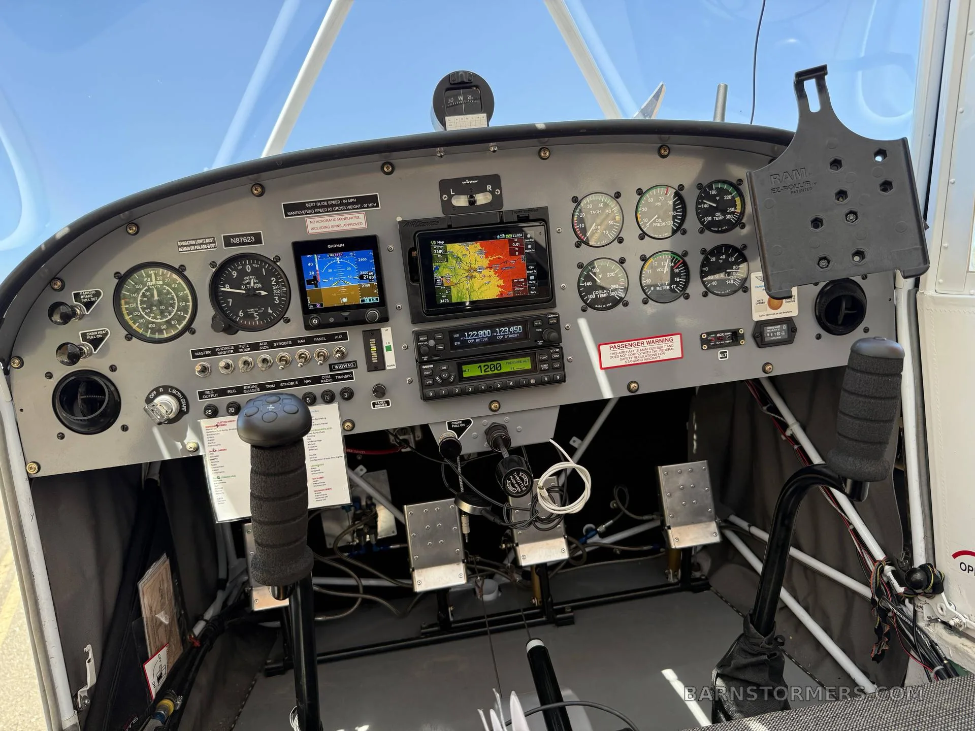 The cockpit of a small aircraft, showing the instrument panel with analog gauges and digital displays, and flight controls.
