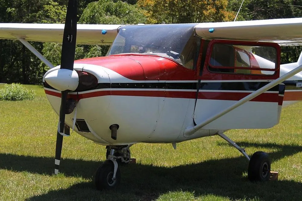 A close-up front view of a red and white single-engine propeller aircraft (N6924X) on a grassy field.
