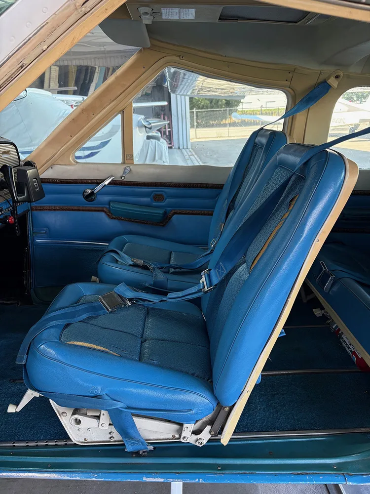 The blue front and middle seats of a Cessna 177 aircraft cabin, viewed from the side.
