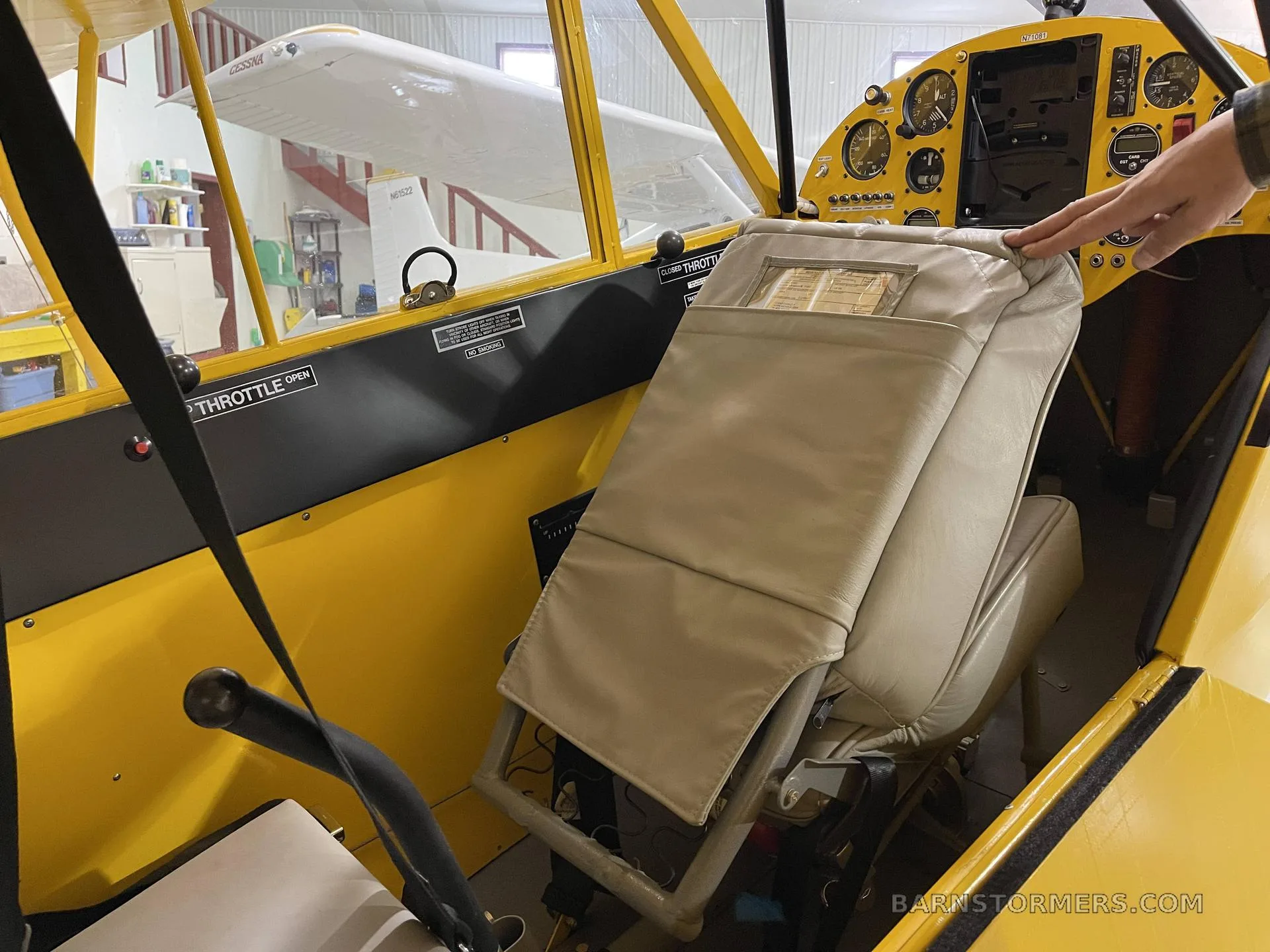 The interior of a yellow aircraft showing beige seats and part of the instrument panel.