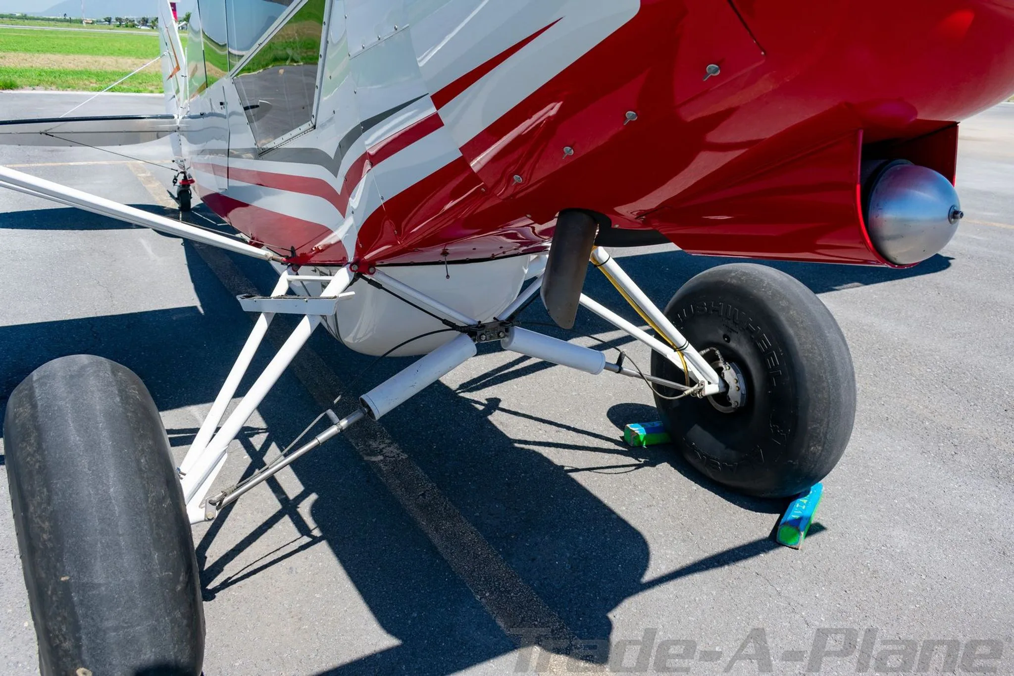 A close-up view of the large tundra tires and landing gear of a red and white Super Cub aircraft.
