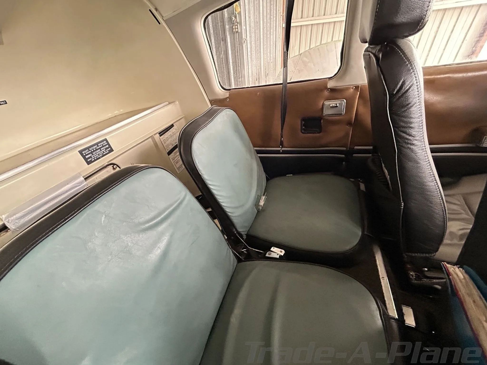 The light blue rear cabin seats of an aircraft, with brown side panels.