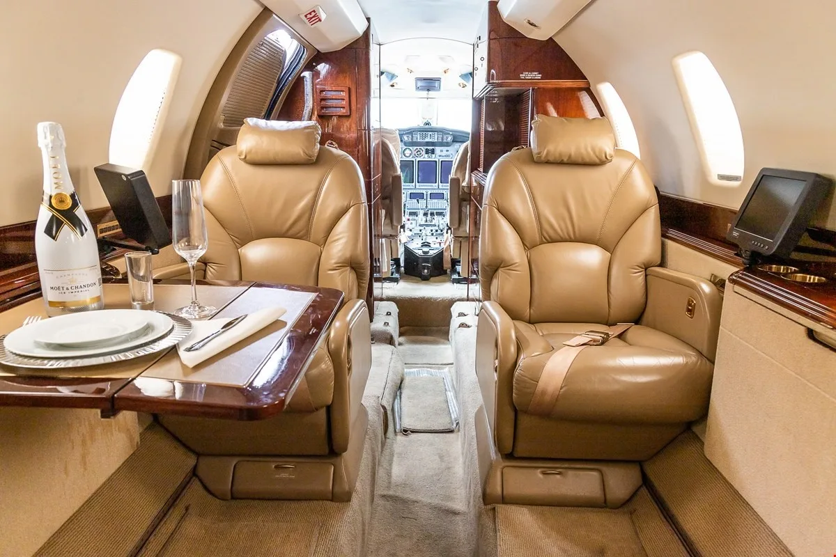 Interior view of the Citation X cabin with leather seats and a table set for dining.
