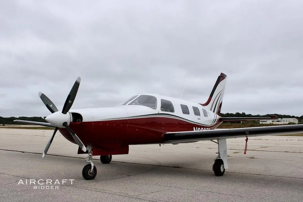 A white and red single-engine turboprop aircraft, registration N92358, parked on an airport tarmac under an overcast sky.