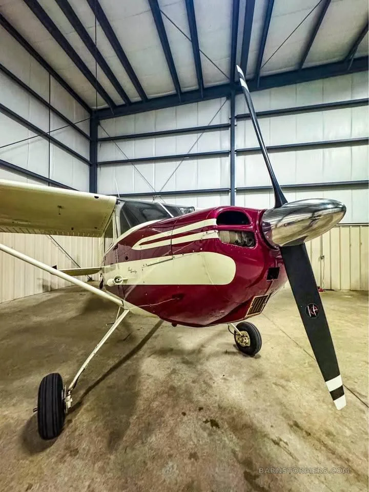 A vintage-style cockpit with a red instrument panel, white yokes, and red quilted interior.