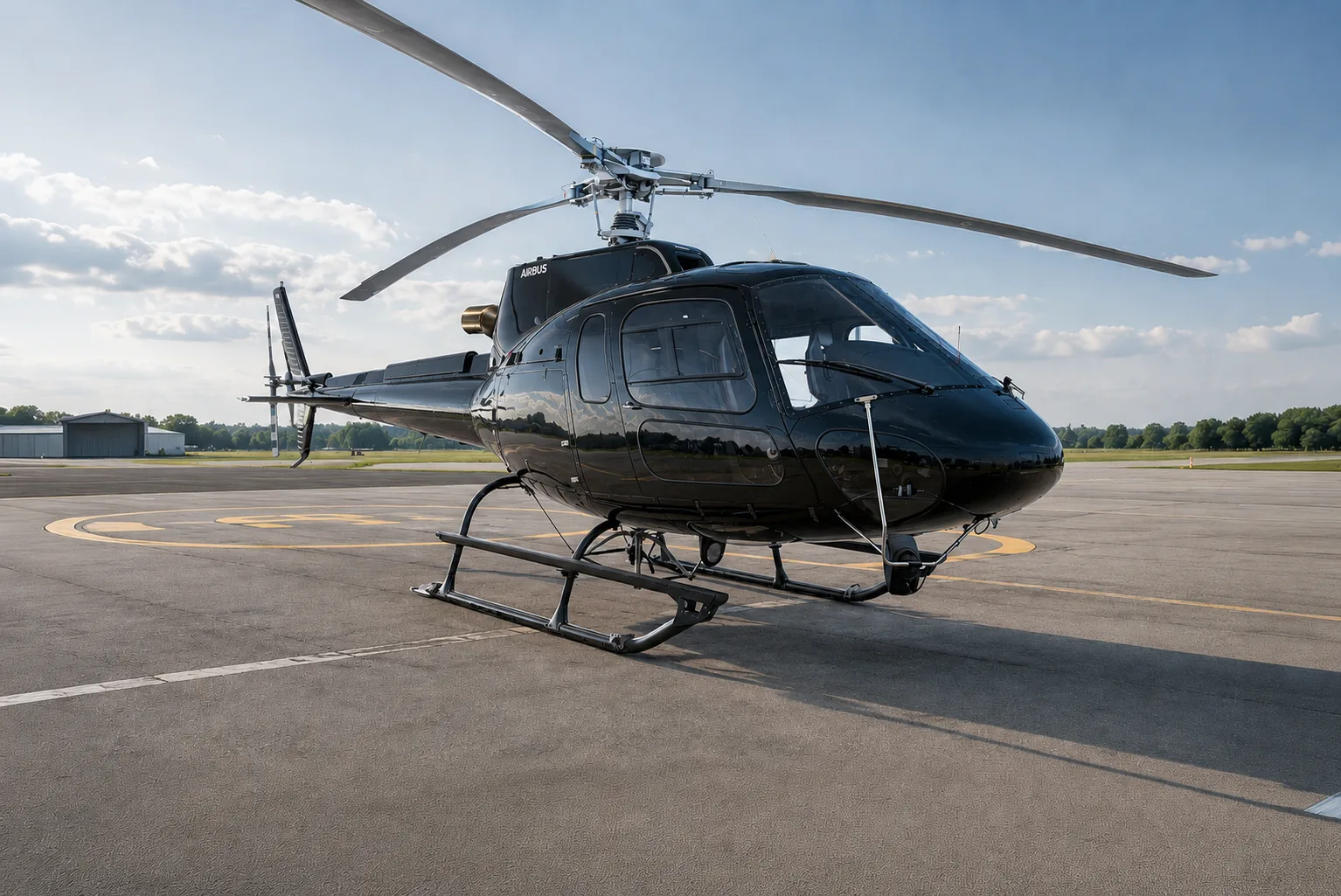 A sleek black Airbus H125 helicopter is parked on an airport tarmac under a partly cloudy sky.