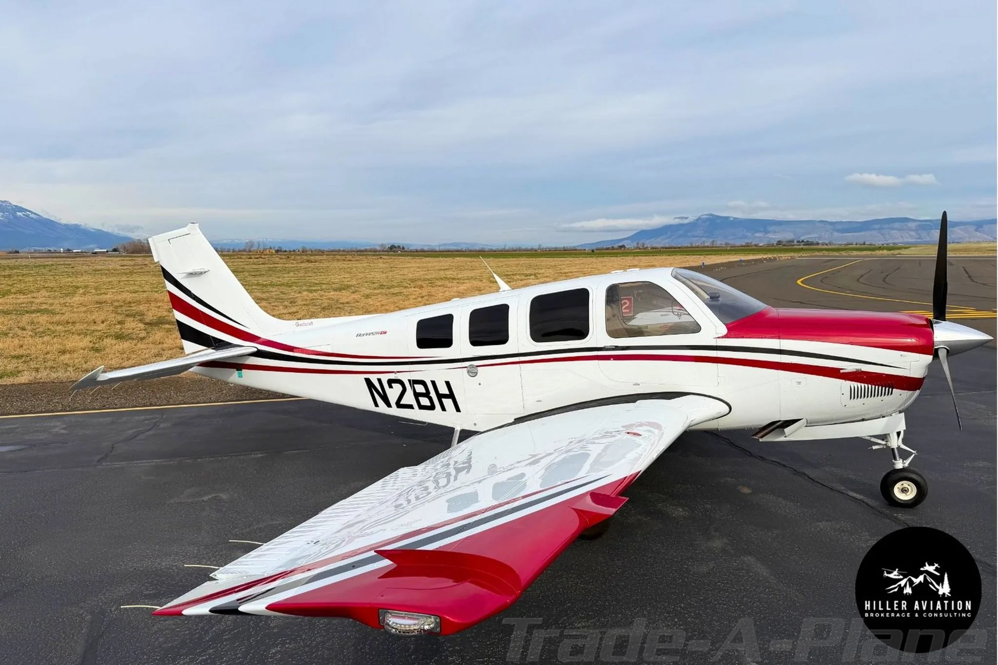 Side view of a white and red Beechcraft Bonanza G36 (N2BH) parked on an airfield.