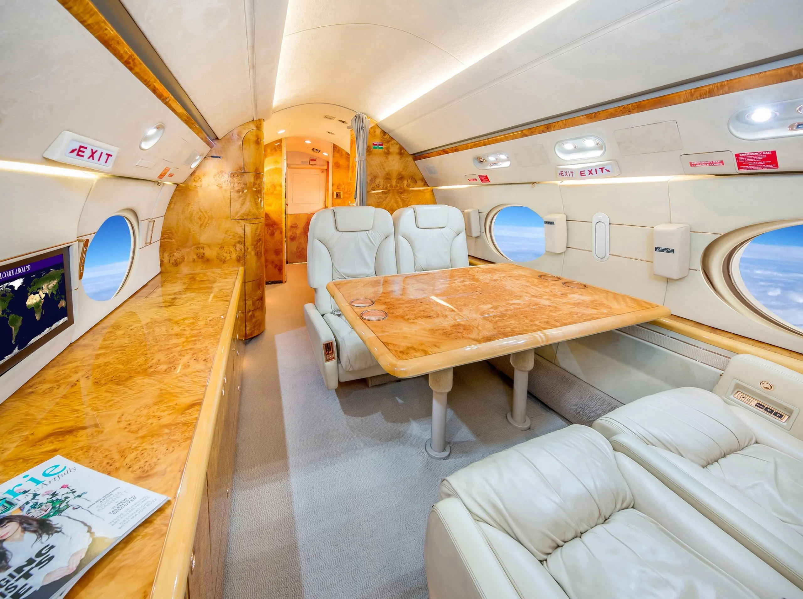 Aircraft interior with cream-colored leather seats and wood trim.