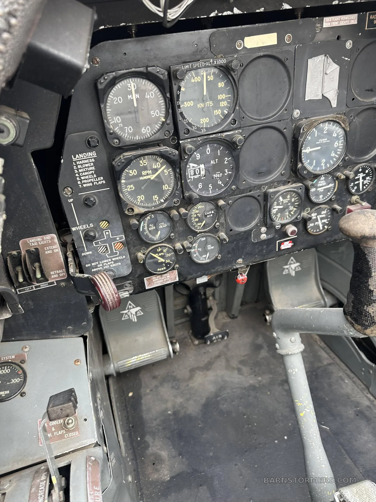 A view of the instrument panel, rudder pedals, and floor of a vintage aircraft cockpit.