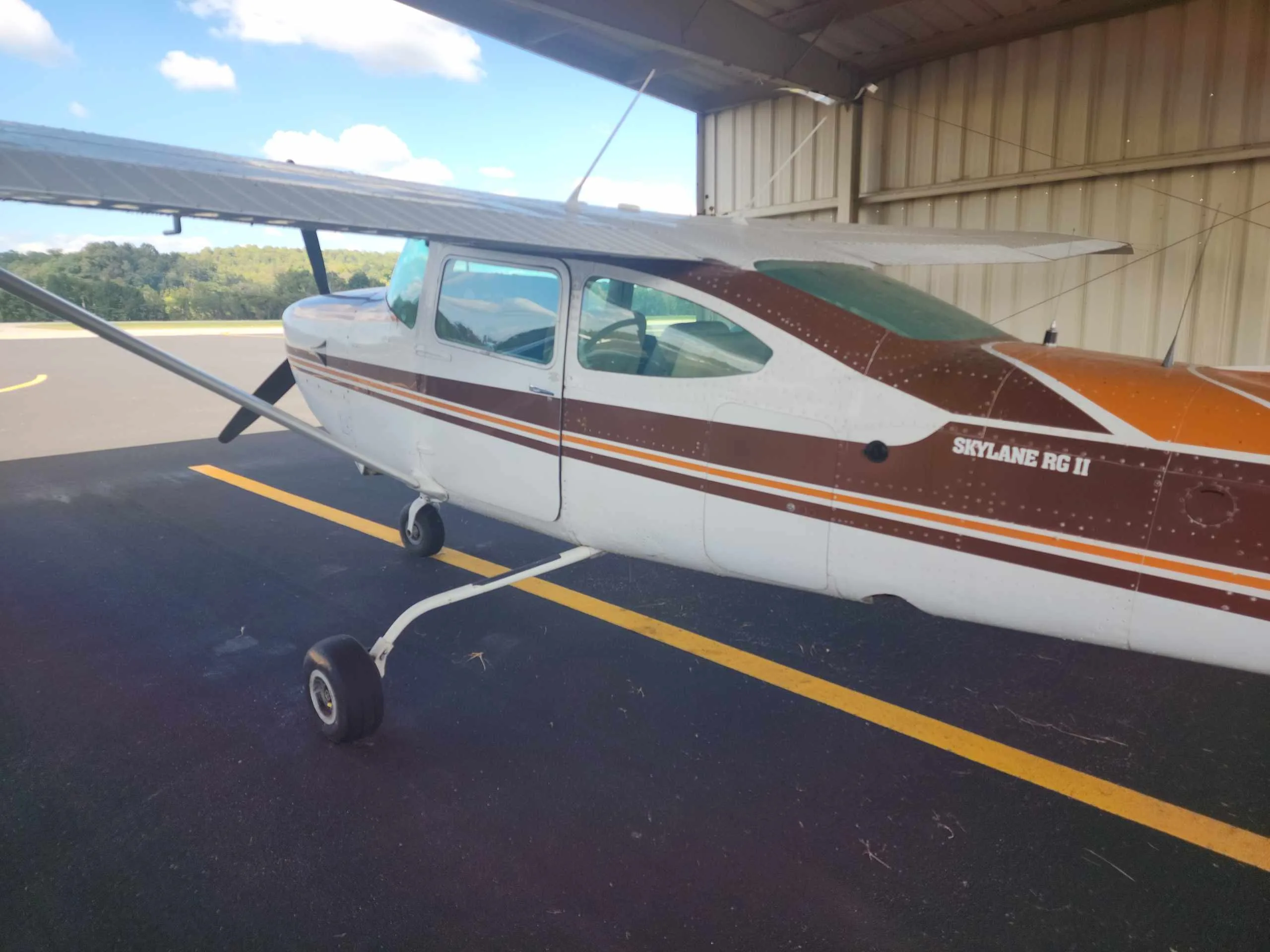 Rear-side view of a white and brown Cessna Skylane RG II (N5019S) parked in a hangar.