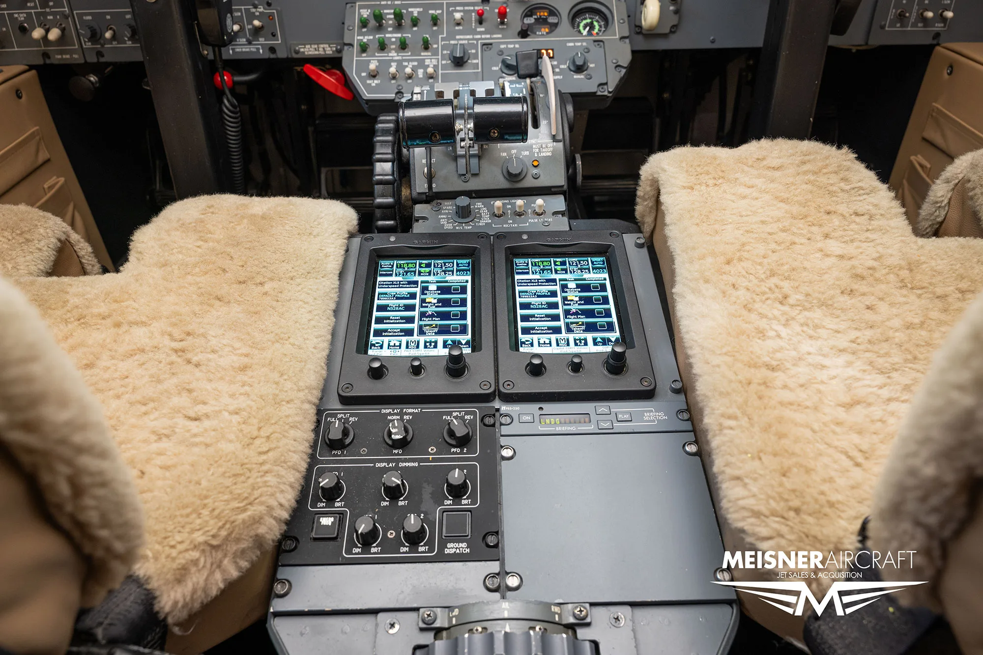 A close-up view of the center console in an aircraft cockpit, showing controls and two small digital displays, with a 'Meisner Aircraft' logo.