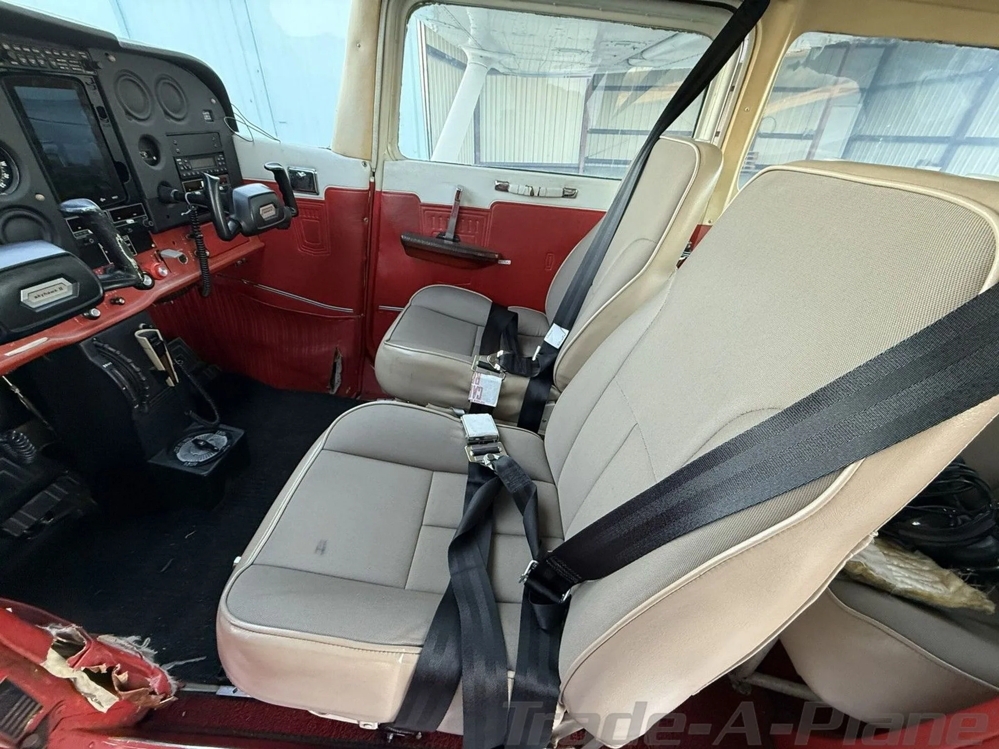 The beige and red interior cabin of a Cessna 172N, showing the front seats and part of the instrument panel.