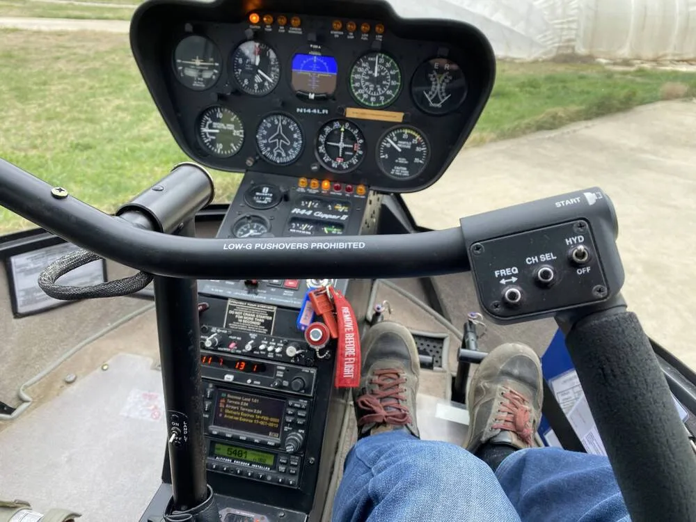 A view from the pilot's seat showing the instrument panel of the Robinson R44 Clipper II helicopter, N144LR, with feet on the pedals.