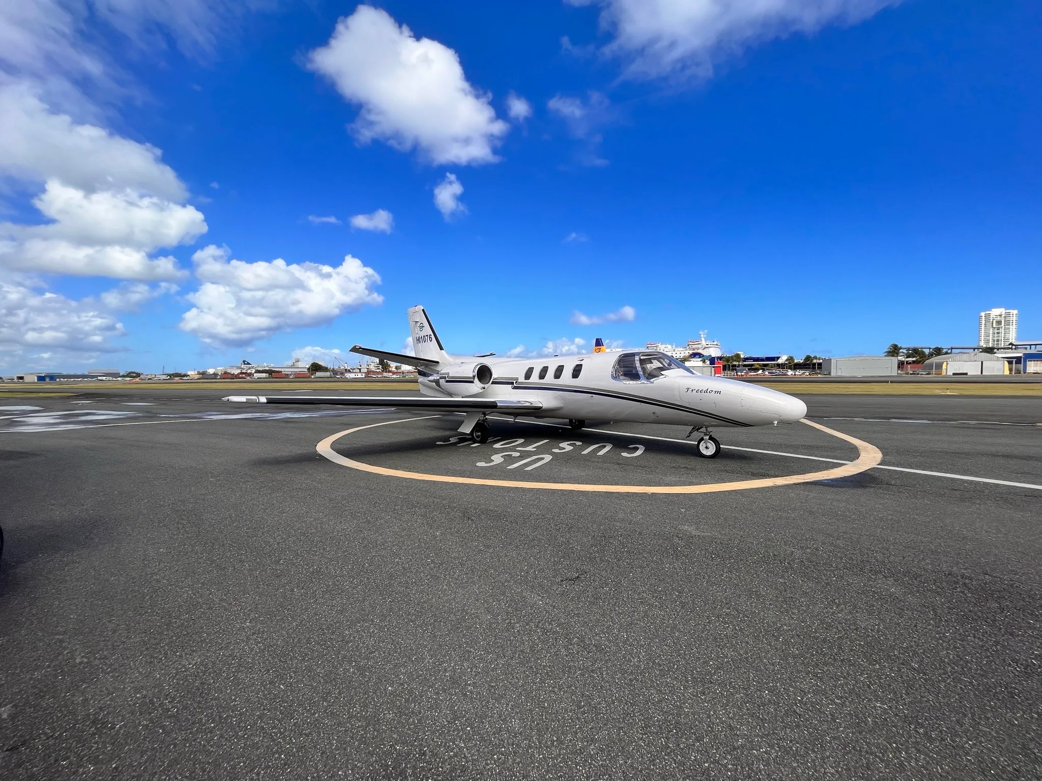A white Cessna Citation Mustang with black and gold stripes sits on the tarmac.