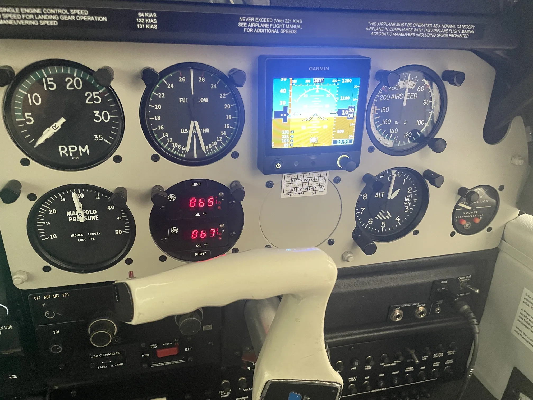 The left side of an aircraft's instrument panel, showing engine gauges, a Garmin display, and a control yoke.