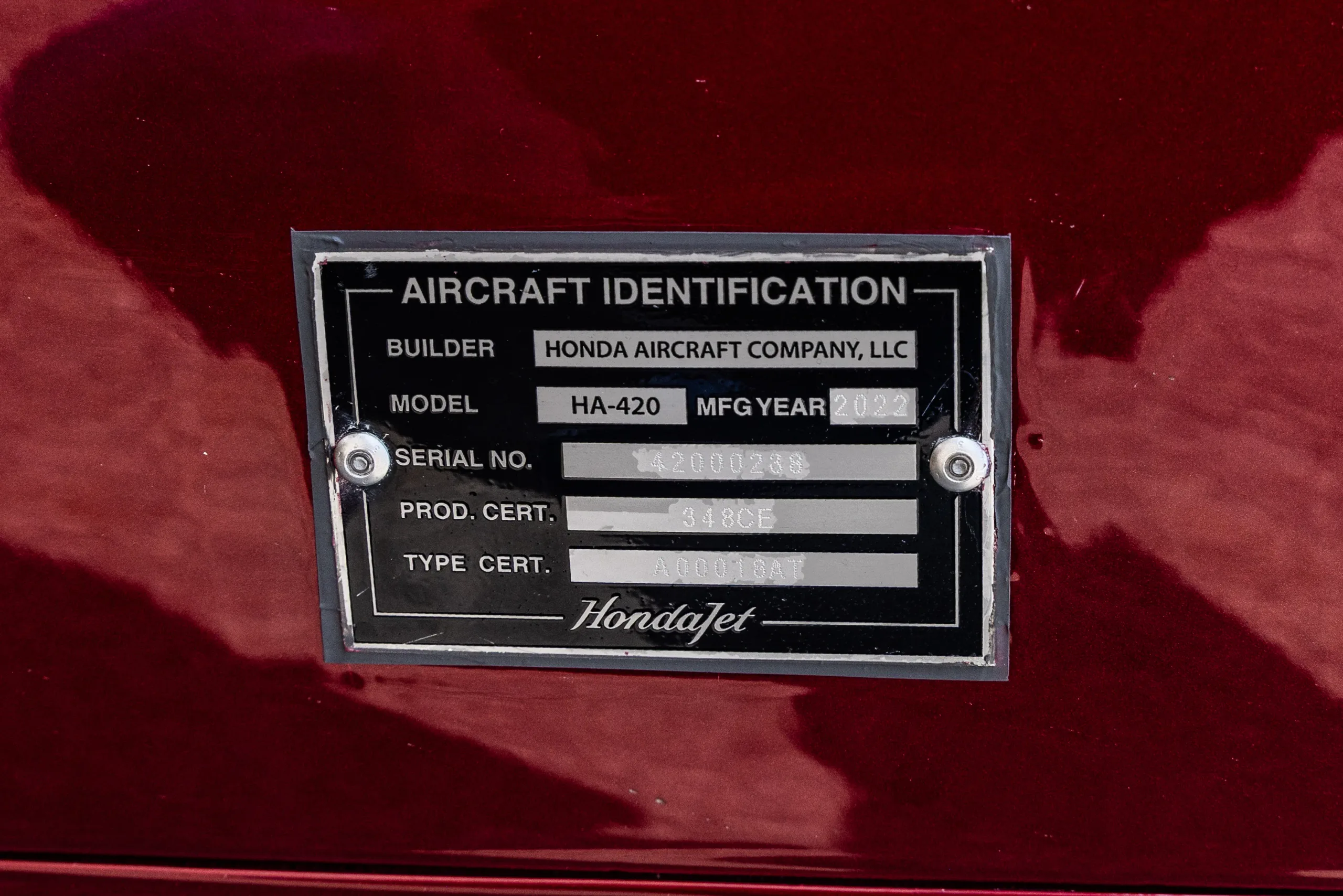 A close-up of a HondaJet HA-420 aircraft identification plate showing model, serial number, and manufacturer.