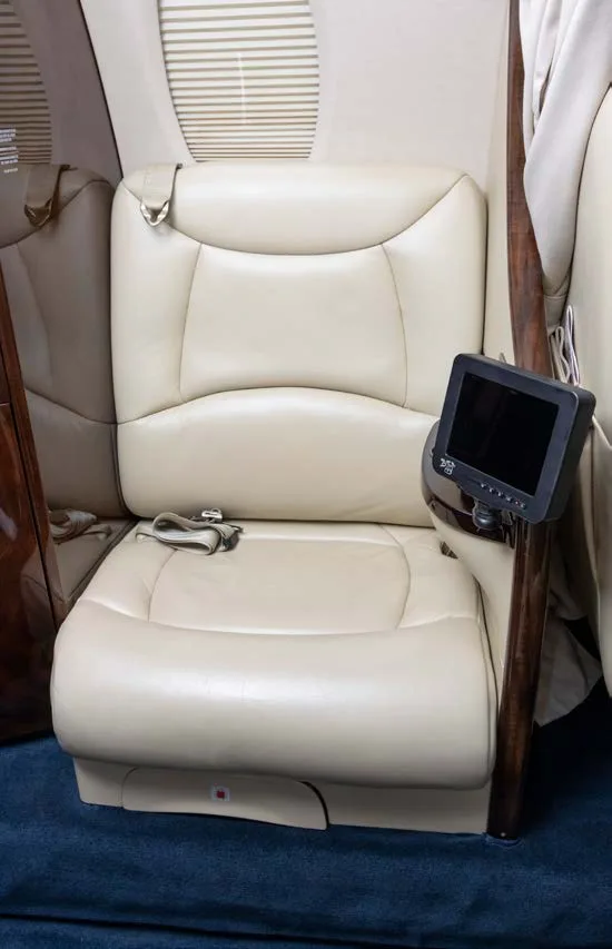 A single cream leather cabin seat with a small entertainment screen attached to the side.