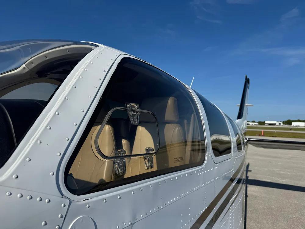 A side view of the aircraft's white fuselage shows the cabin windows and tan interior seats.