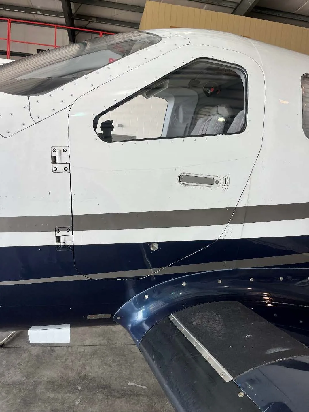 A close-up view of the cockpit door and fuselage of a white and blue aircraft.