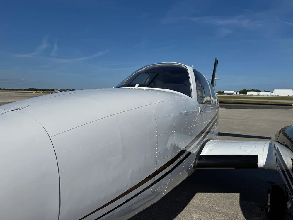 A close-up view captures the white fuselage and cockpit windshield of the twin-engine aircraft on an airfield.
