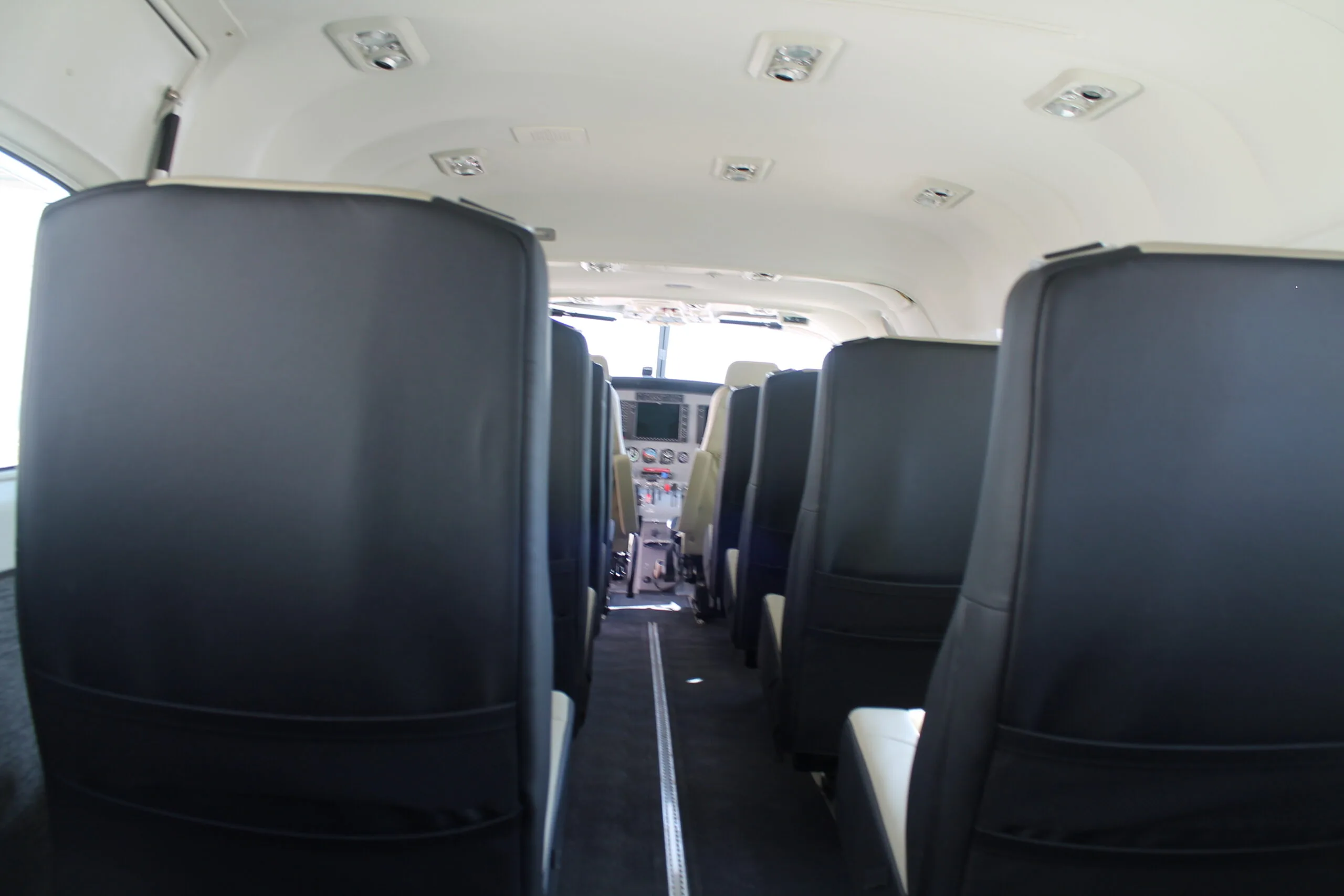 The aircraft cabin features rows of dark-colored seats, looking towards the cockpit.