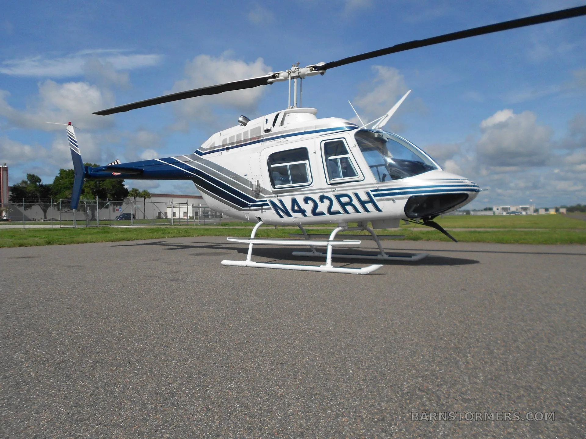 A white and blue Bell 206 helicopter (N422RH) parked on an asphalt apron, viewed from a slightly different angle.