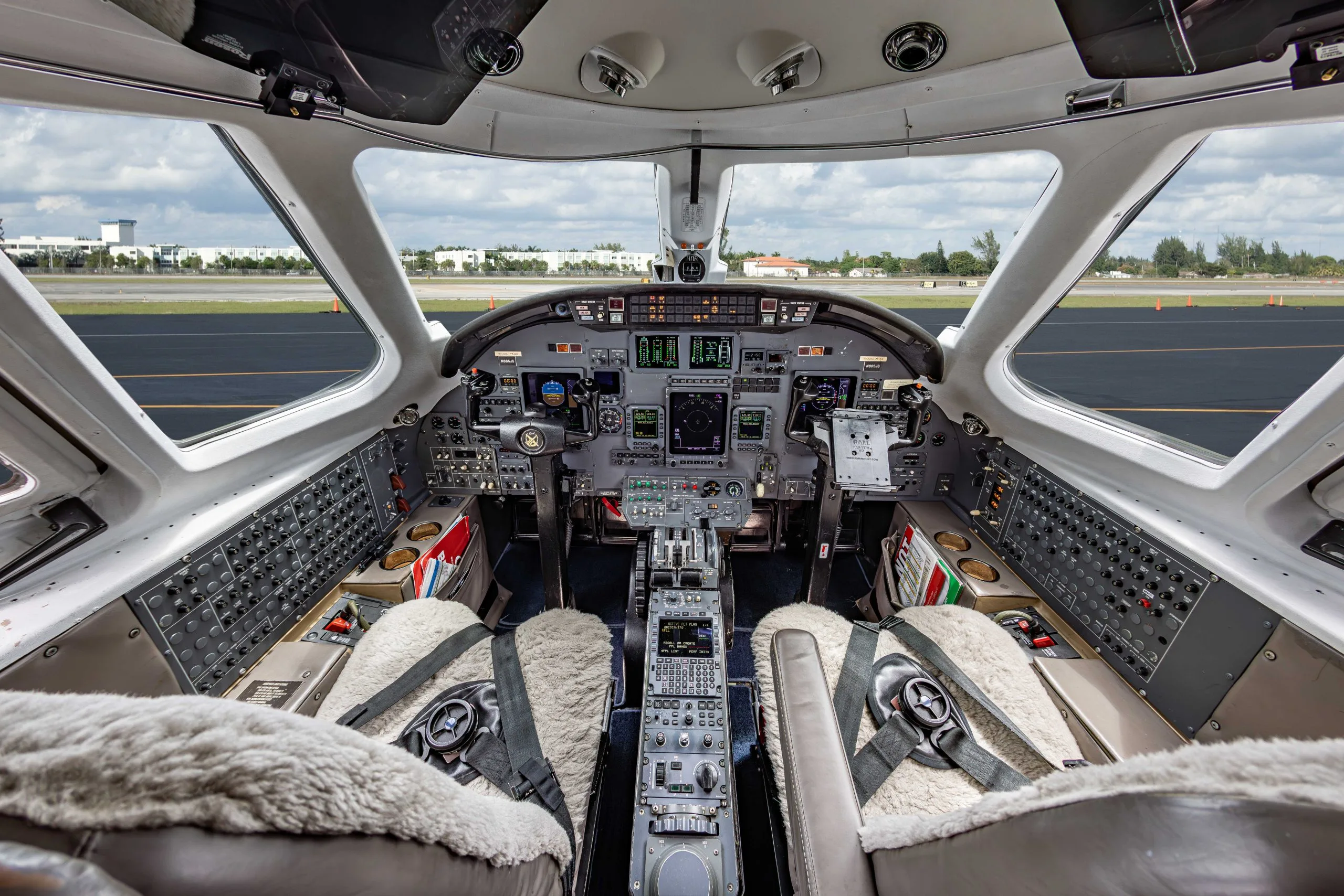 View of the aircraft's cockpit with instrument panel and sheepskin seat covers.