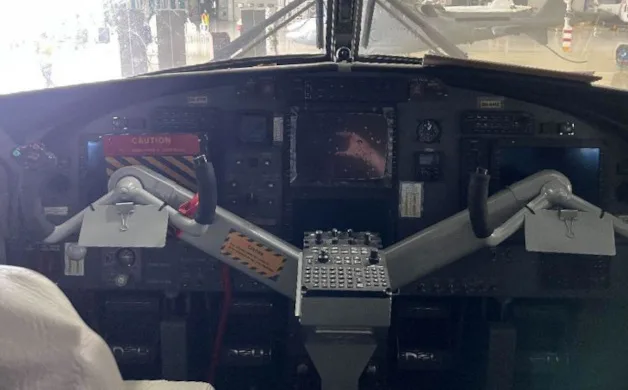 The cockpit of an aircraft, showing the instrument panel, yokes, and throttle quadrant.