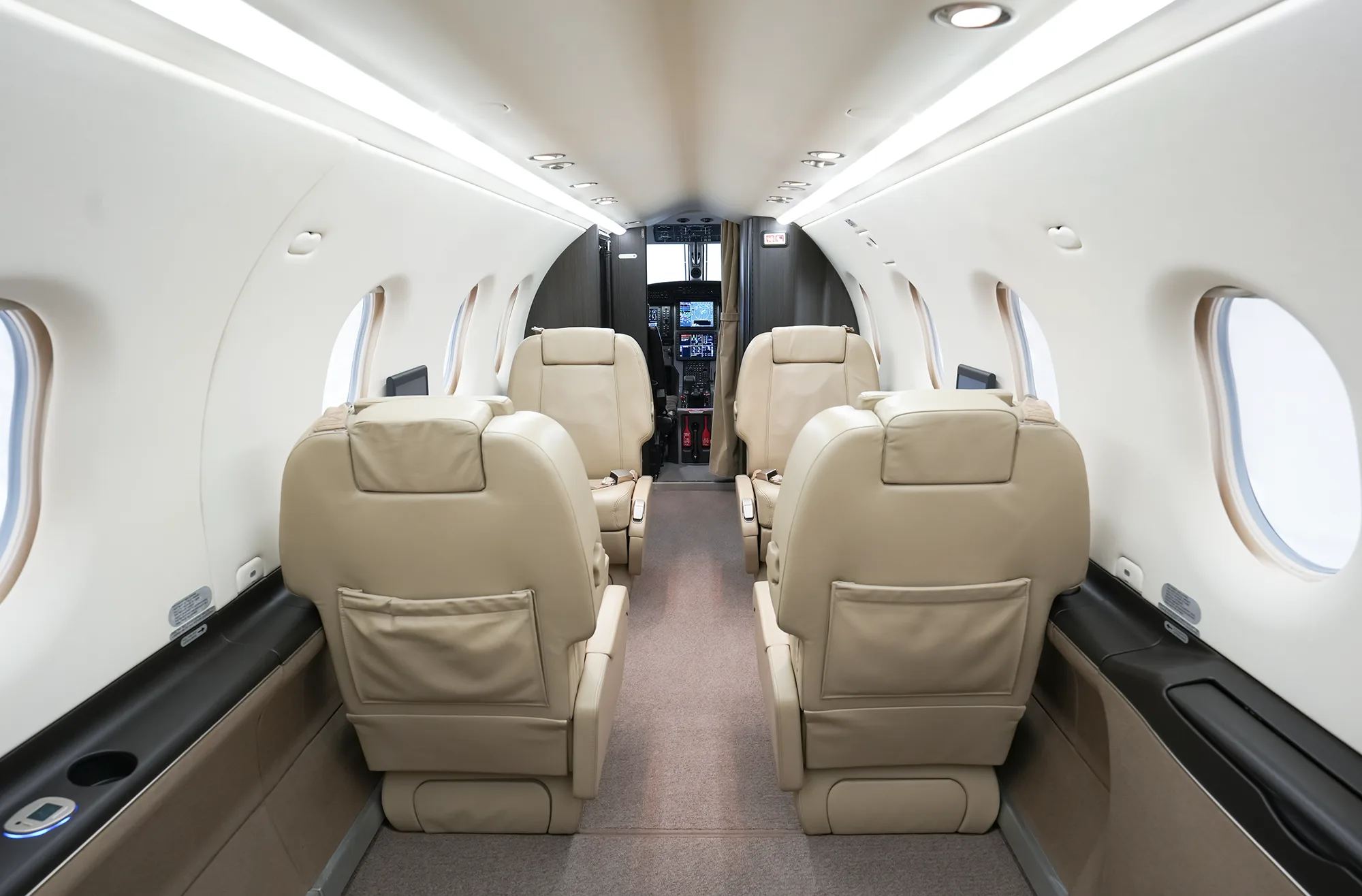 The aircraft cabin interior with beige leather seats, looking forward towards the cockpit.