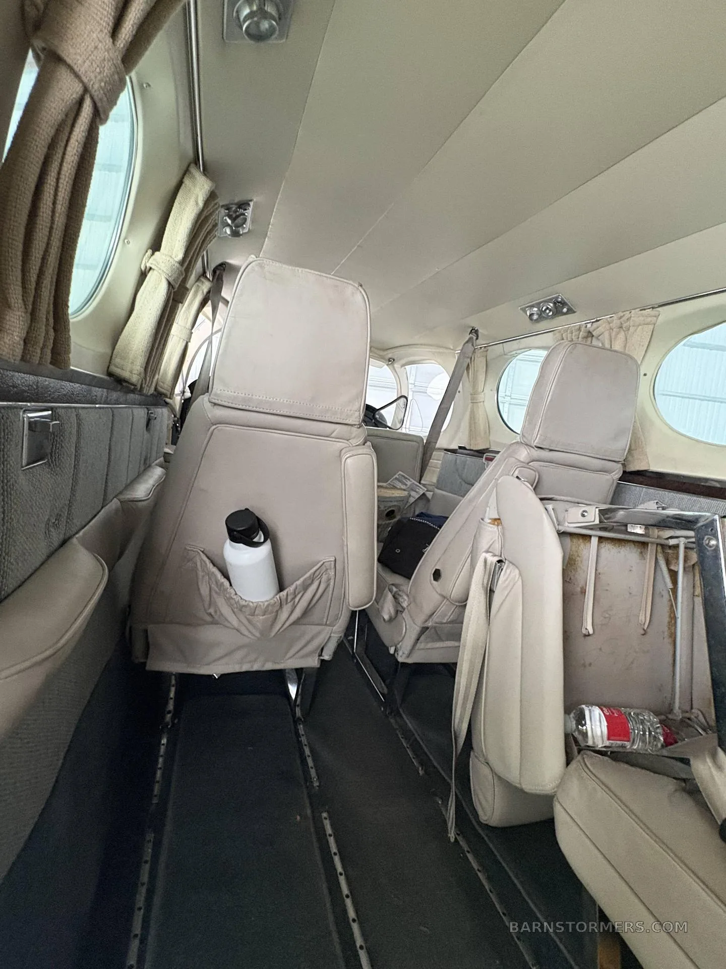 The beige leather passenger cabin interior of a small aircraft, showing two rows of seats.