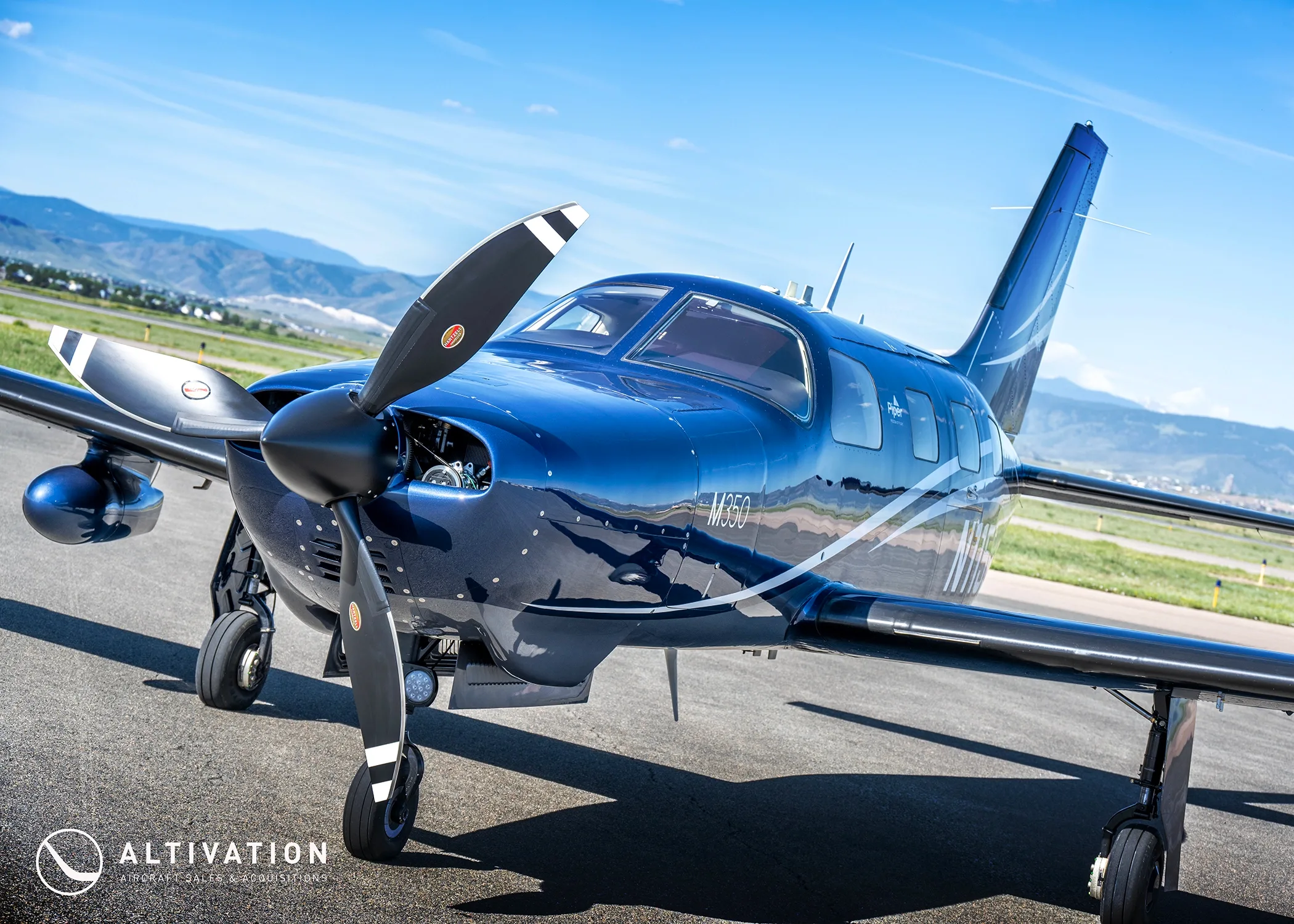 A close-up front view of the dark blue Piper M350, tail number N115DW, on a sunny tarmac.