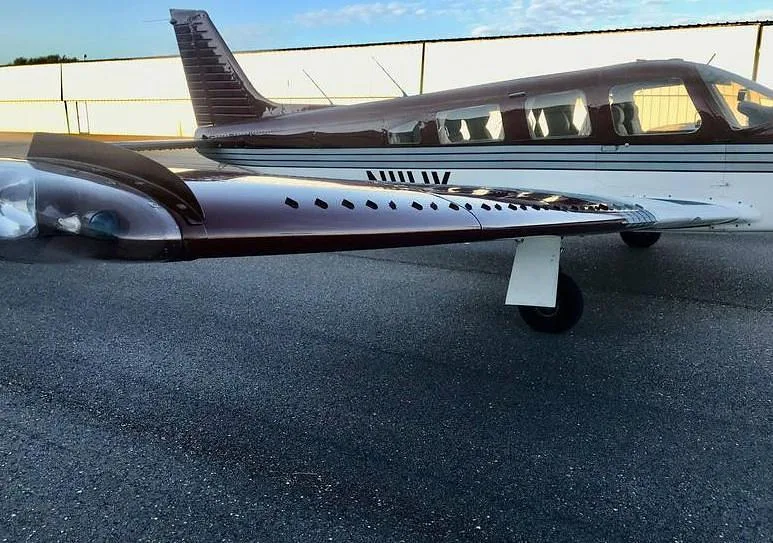 A close-up side view of the burgundy and white aircraft, showing the wing and fuselage.