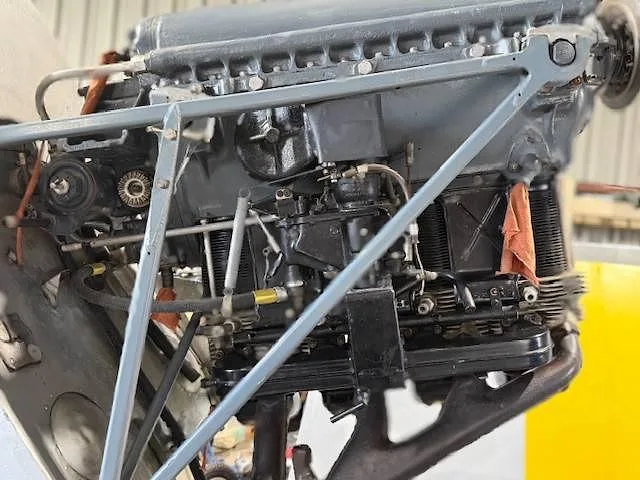A close-up view of a grey aircraft engine with exposed cylinders and various mechanical components.