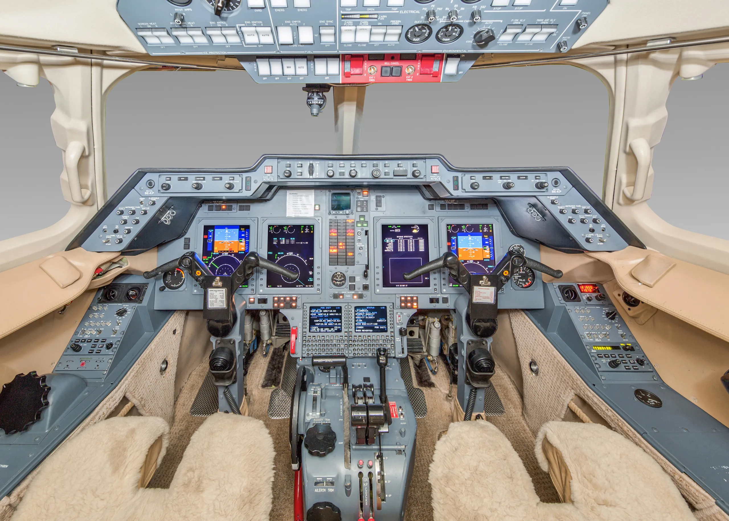 The cockpit of a private jet, showing the instrument panel, multiple display screens, and control yokes.