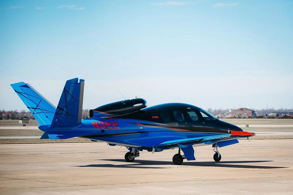 A Cirrus Vision Jet (N3EE) in blue and black paint scheme, parked on an airfield.